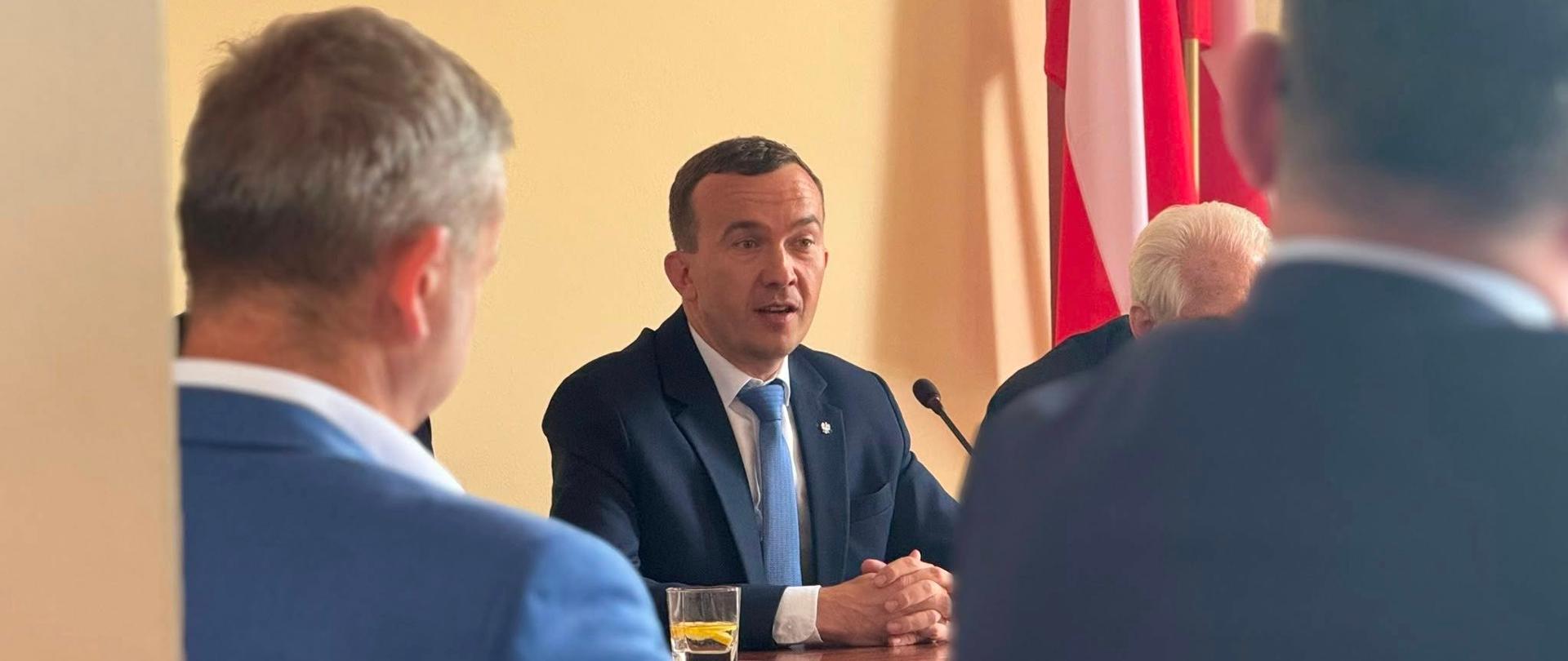 Kilka mężczyzn siedzi przy stole i debatuje