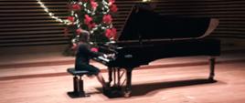 Dziewczynka gra na fortepianie na estradzie sali koncertowej.