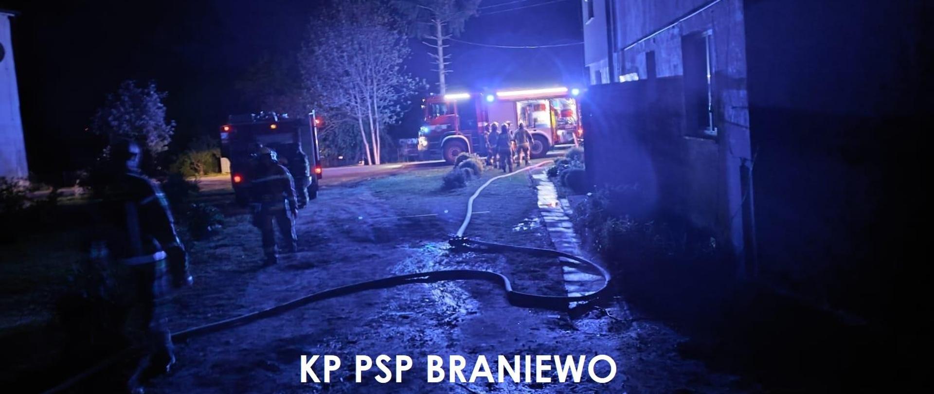 Zdjęcie zrobione nocą. Strażacy podczas akcji gaśniczej. Dalej widać samochody strażackie na światłach. Oświetlaja teren.