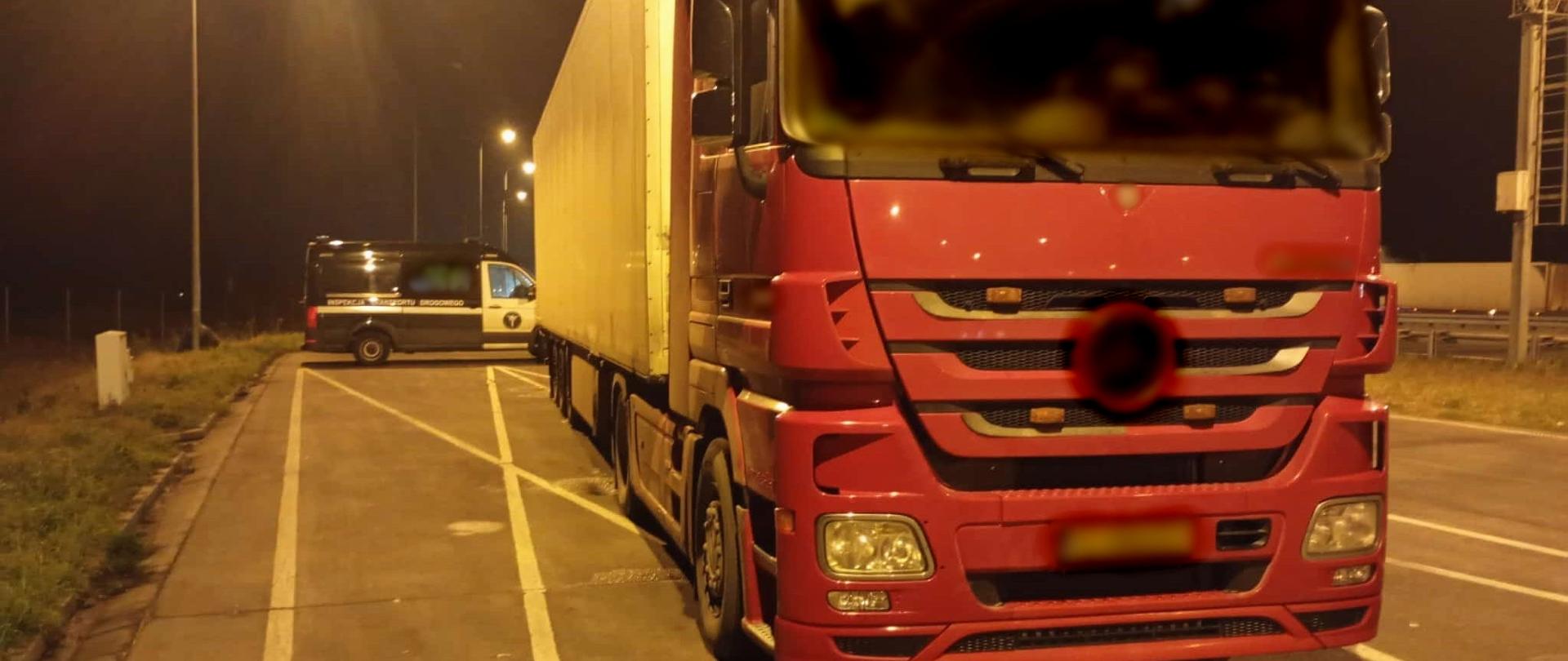 Na pierwszym planie: przód ciągnika siodłowego z podpiętą naczepą - chłodnią. W tle: za kontrolowanym zestawem ciężarowym stoi oznakowany furgon mazowieckiej Inspekcji Transportu Drogowego.