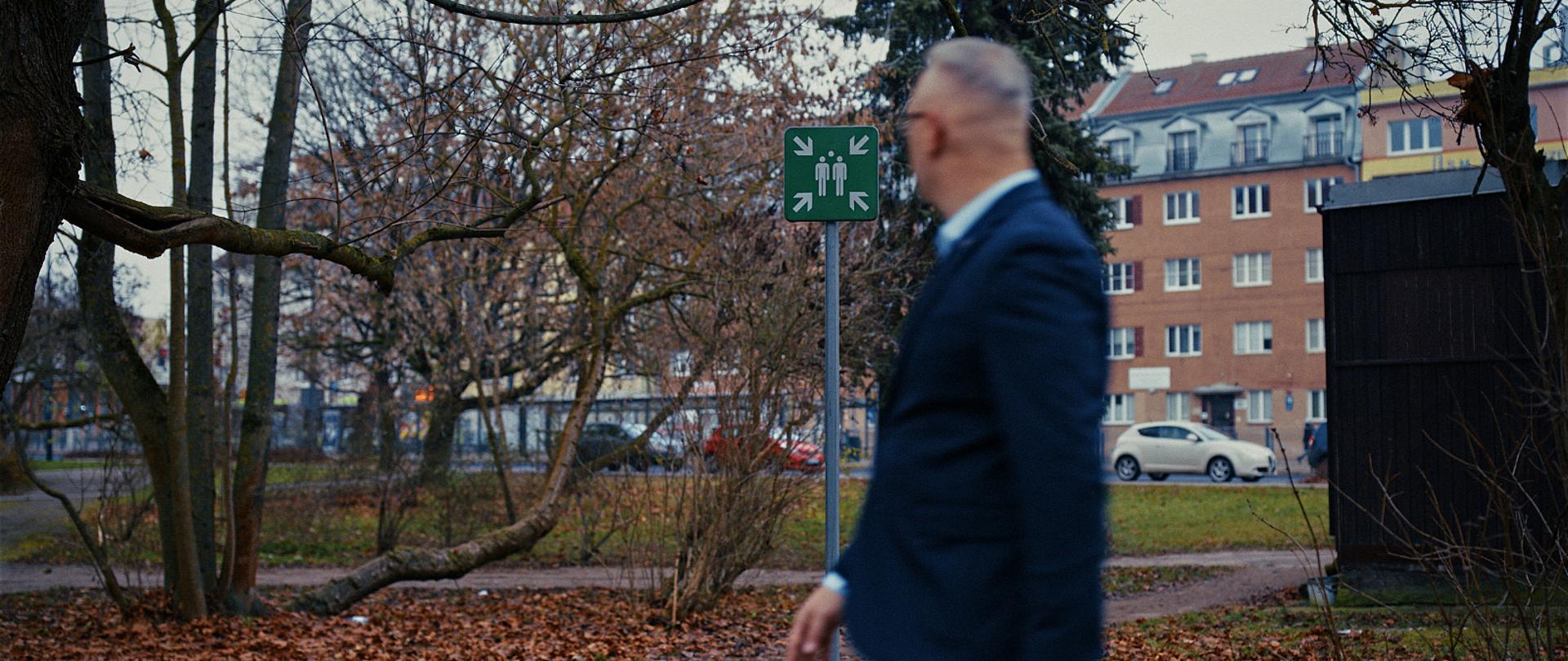 Mężczyzna w garniturze jest rozmazany, idzie po parku 