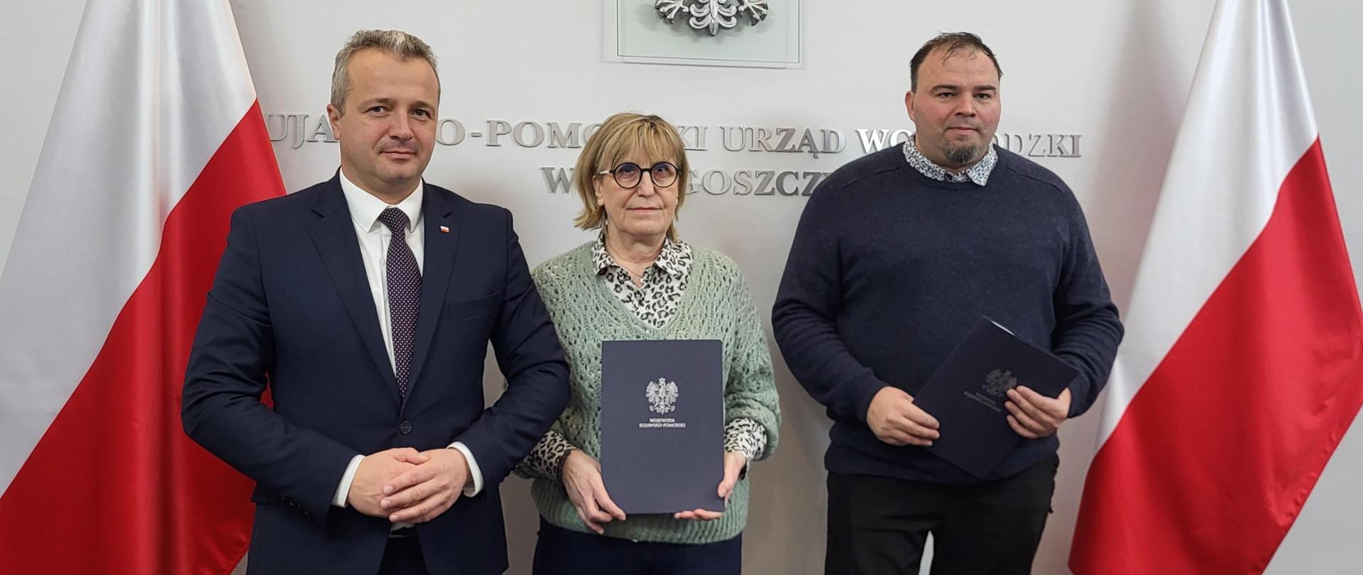 
Trzy osoby podpisujące umowę
