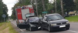 Dwa samochody osobowe po zderzeniu stojące na jednym pasie jezdni. Jeden z samochodów uderzył w tył drugiego. W tle samochód ratowniczo-gaśniczy.