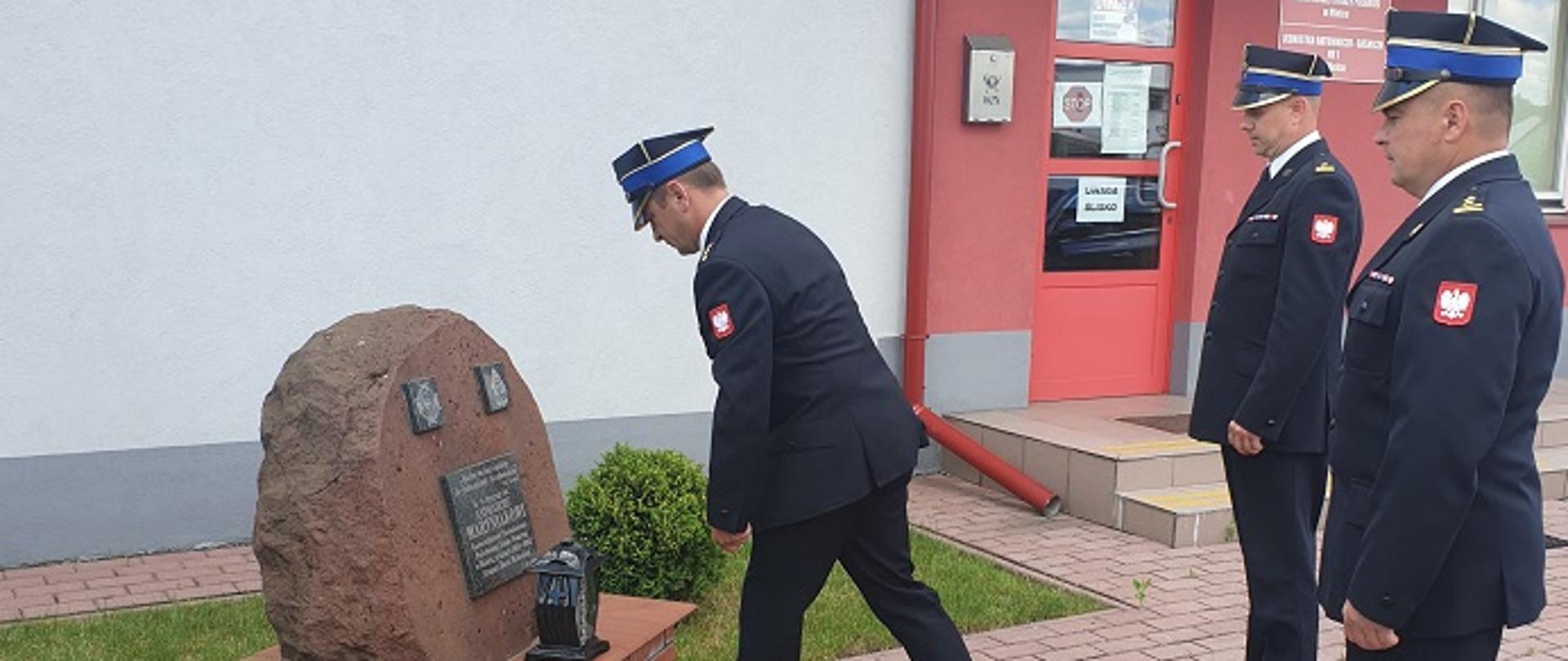 Przed obeliskiem na tle komendy powiatowej PSP w Mielcu delegacja funkcjonariuszy ubranych w mundury galowe składa hołd j ś.p. st. bryg. Antoniemu Maryniakowi, byłemu komendantowi powiatowemu PSP w Mielcu.