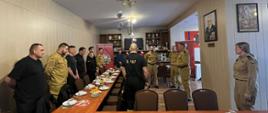 Funkcjonariusze Komendy Powiatowej Państwowej Straży Pożarnej w ubraniach koszarowych podczas spotkania opłatkowego z Komendantem Powiatowym brygadierem Marcinem Mazurkiewiczem