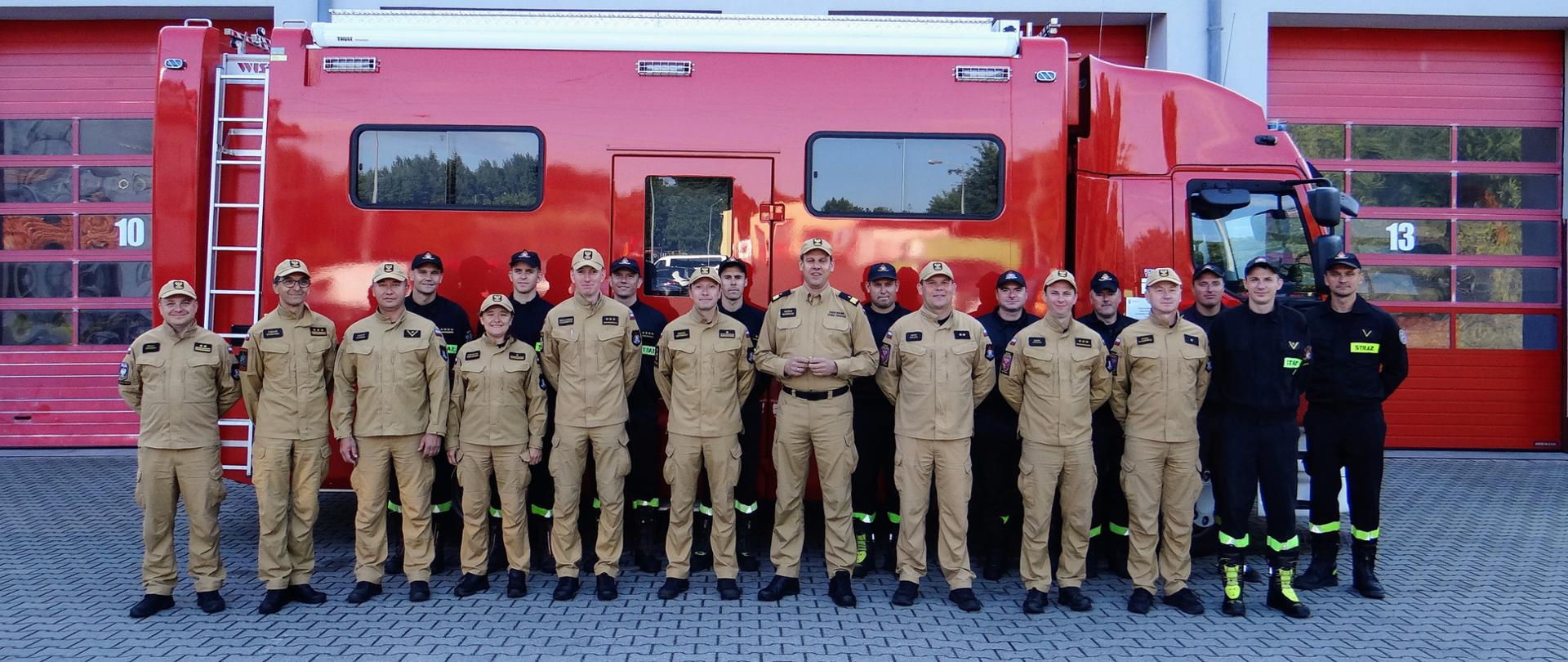 Grupowe zdjęcie strażaków na tle samochodu dowodzenia i łączności