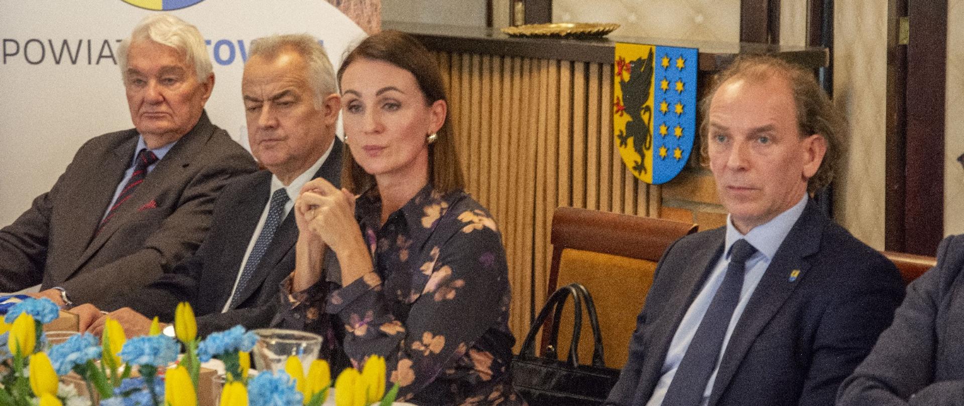 kilkoro osób siedzi przy stole i rozmawia