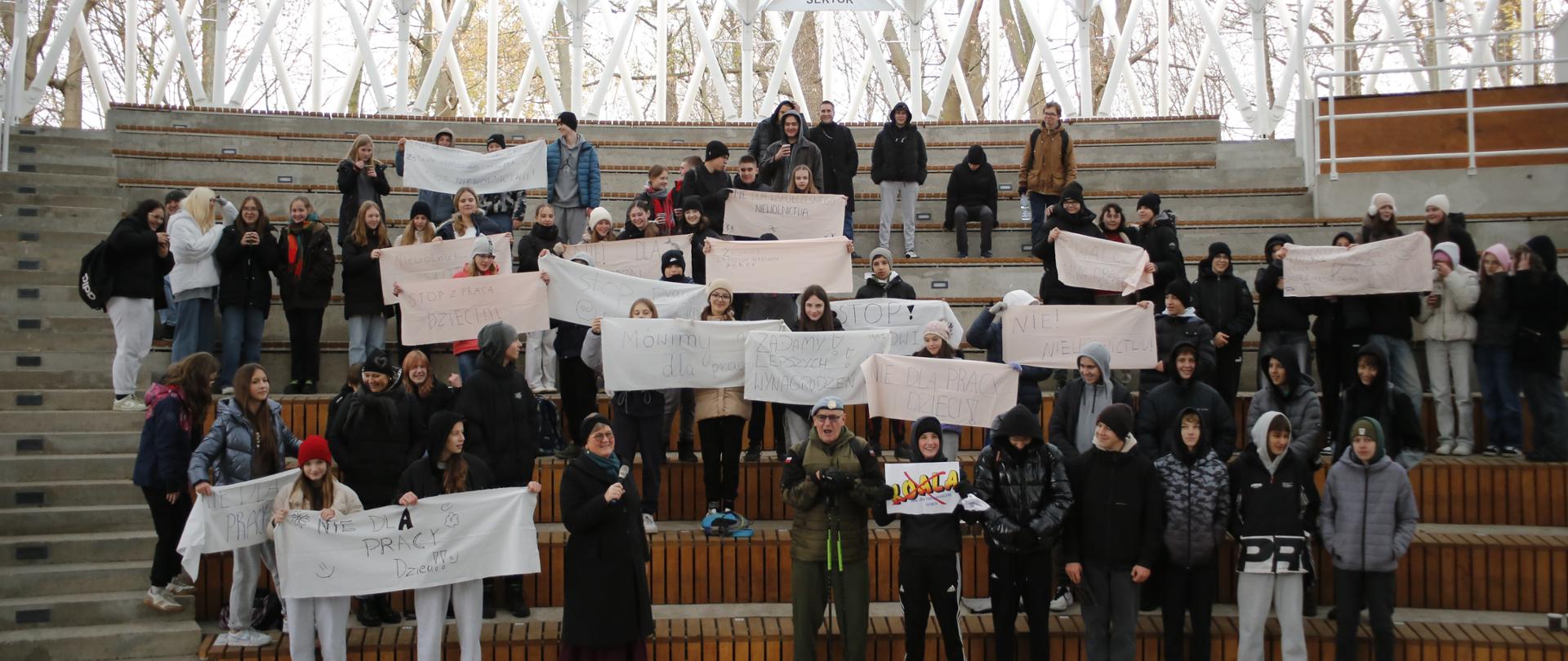 Grupy młodzieży pozują do zdjęcia trzymając banery z hasłami