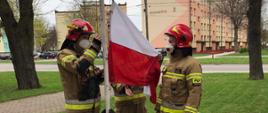 Strażacy przygotowują się do wciągnięcia flagi na maszt