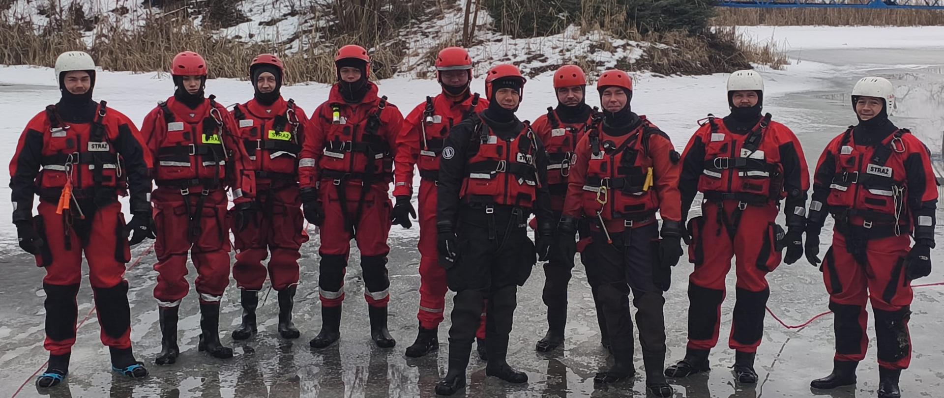 Szkolenie doskonalące w zakresie ratownictwa lodowego. Strażacy ubrani w skafandry nurkowe podczas szkolenia na zamarzniętym akwenie wodnym, ćwiczą wykorzystanie sprzętu do ratownictwa lodowego oraz technik ratownictwa lodowego i samoratownictwa.