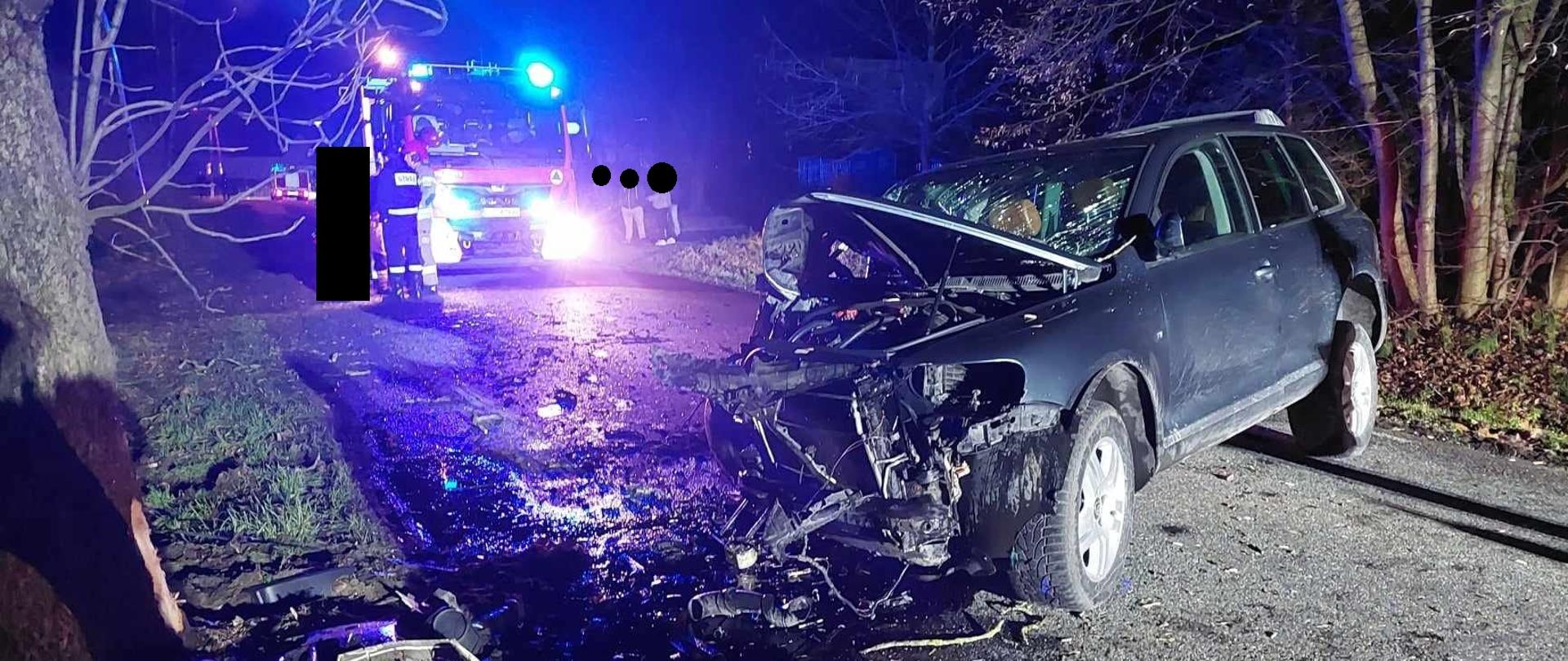 Uszkodzony pojazd na drodze, widok od strony kierowcy, w oddali samochód straży