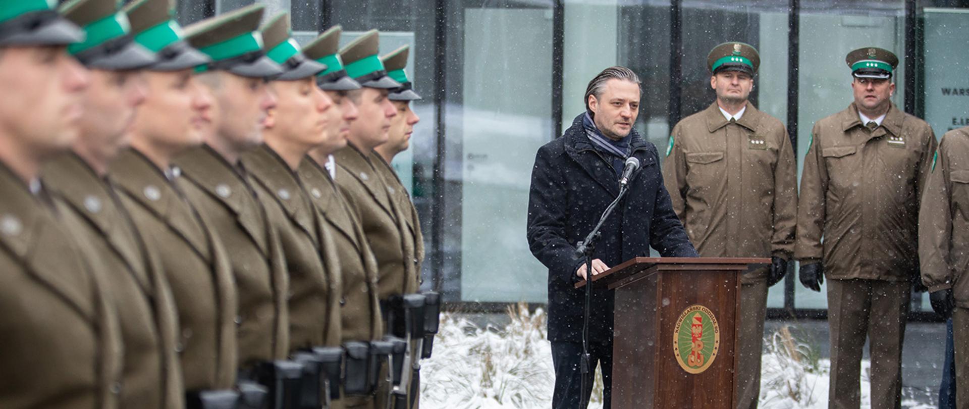 Wiceminister Bartosz Grodecki podczas przemówienia w Radomiu stojący przy mównicy.