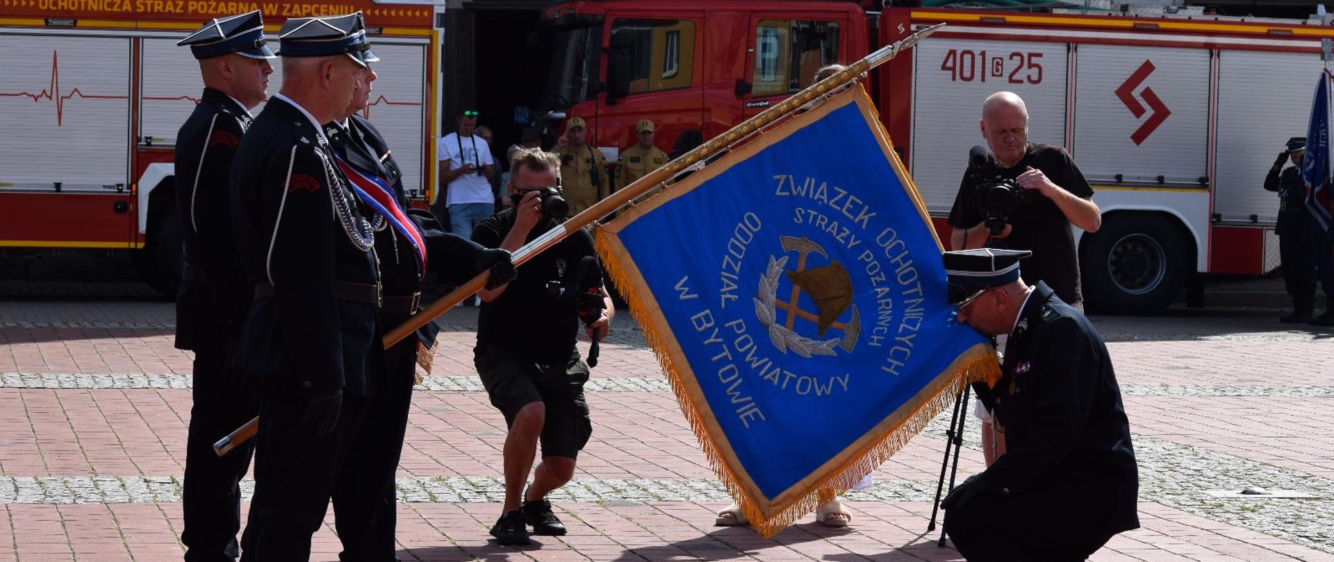 Poczet sztandarowy prezentuje sztandar, przed którym klęczy prezes zarządu powiatowego. 