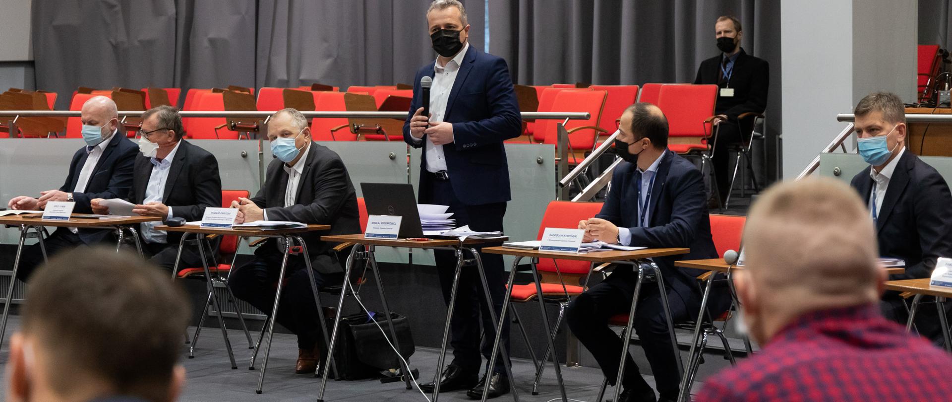 grupa mężczyzn w pomieszczeniu przy stołach 