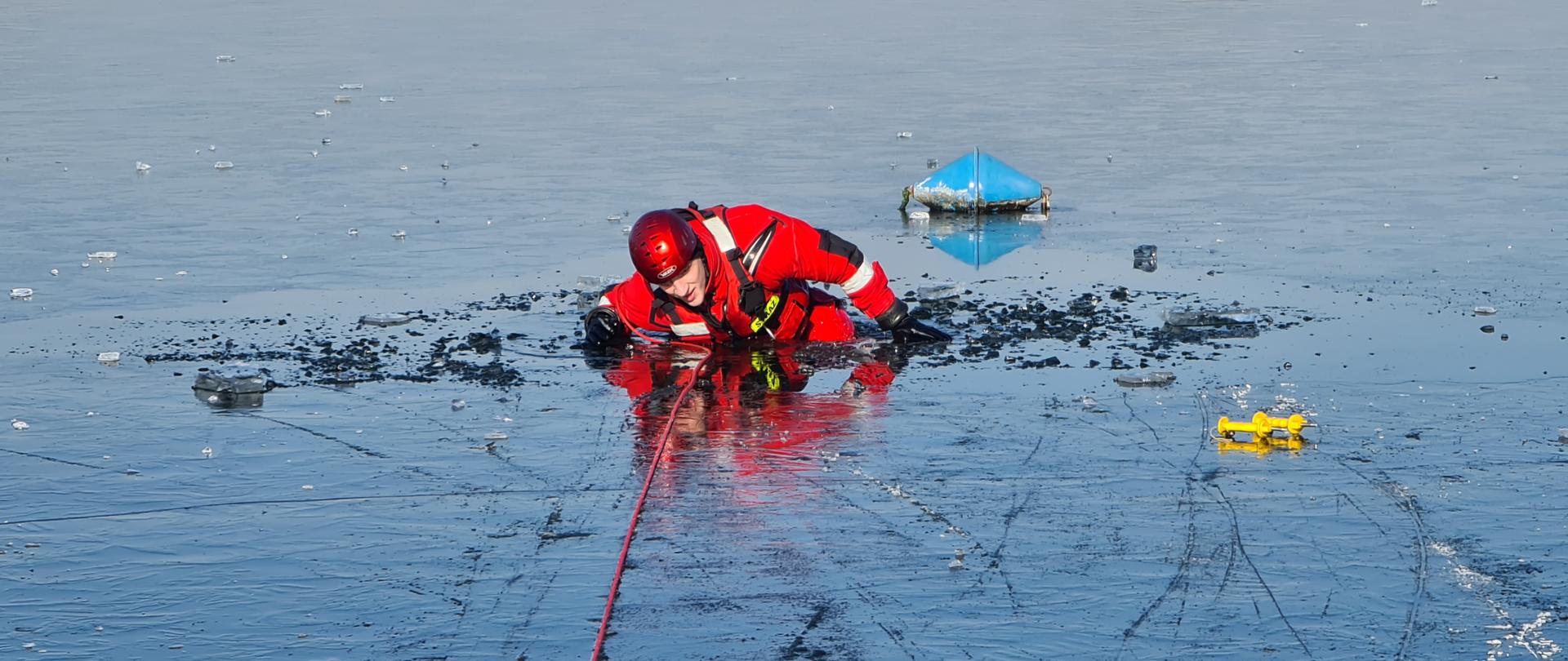 Na zdjęciu widać strażaka podczas ćwiczeń na zamarzniętym akwenie wodnym