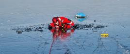 Na zdjęciu widać strażaka podczas ćwiczeń na zamarzniętym akwenie wodnym