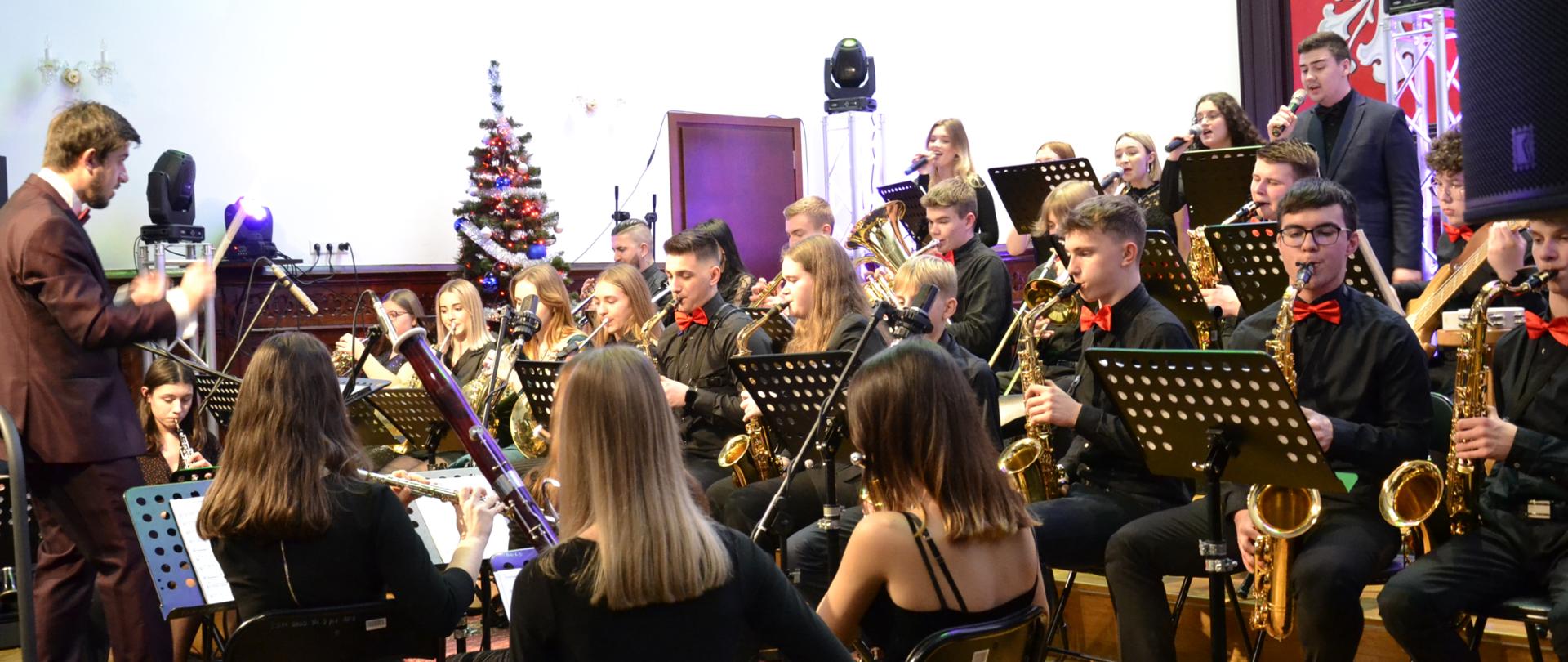 zdjęcie przedstawia orkiestrę dętą PSM II stopnia w Mielcu w Sali królewskiej PSM w Mielcu podczas koncertu kolęd