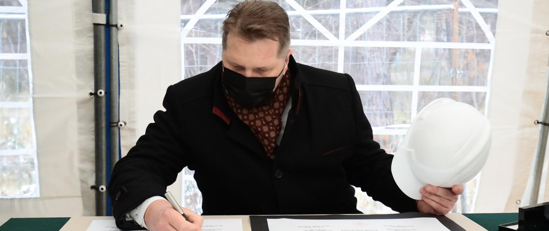 Minister Przemysław Czarnek zainaugurował budowę Specjalnego Ośrodka Szkolno-Wychowawczego w Kozienicach, minister Przemysław Czarnek podpisuje akt erekcyjny.