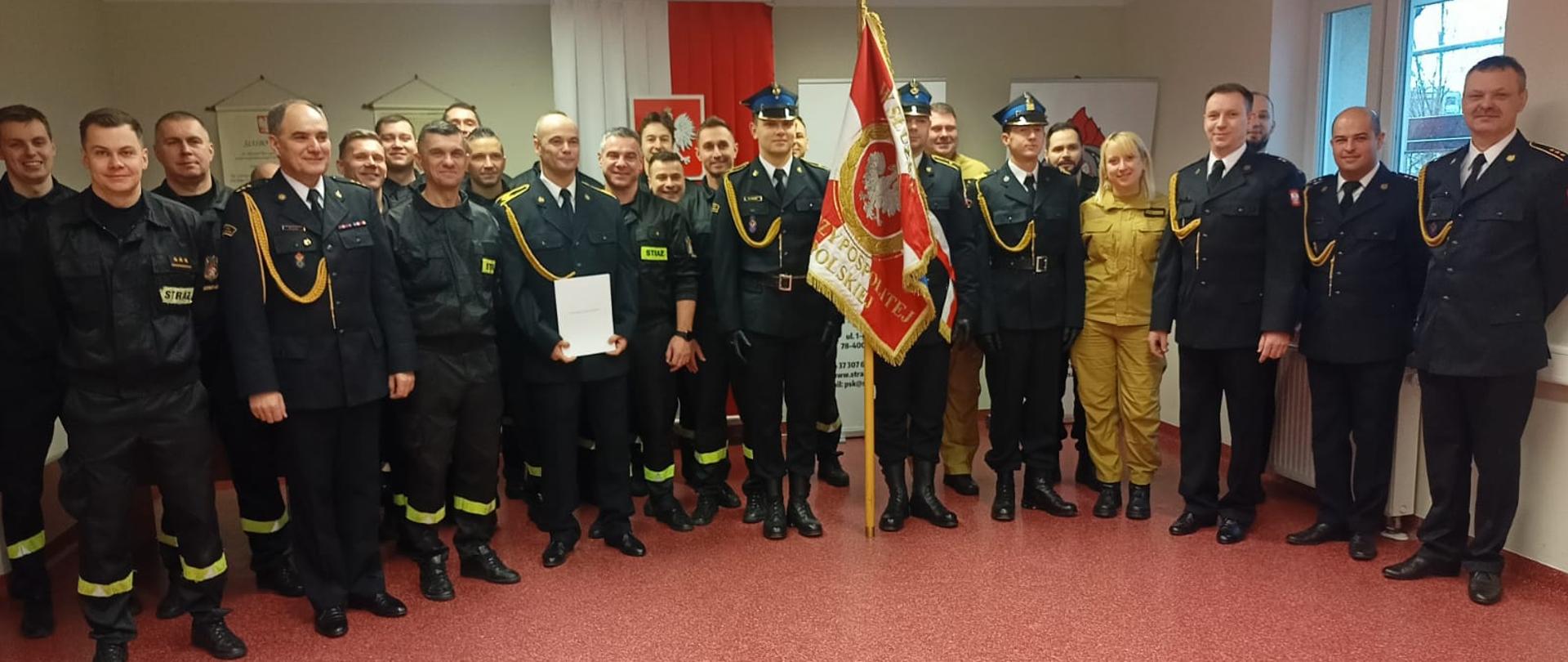 Odejście na zaopatrzenie emerytalne st. ogn. Piotra Korczyńskiego - strażacy ubrani w mundury wyjściowe koloru granatowego ze sznurem.