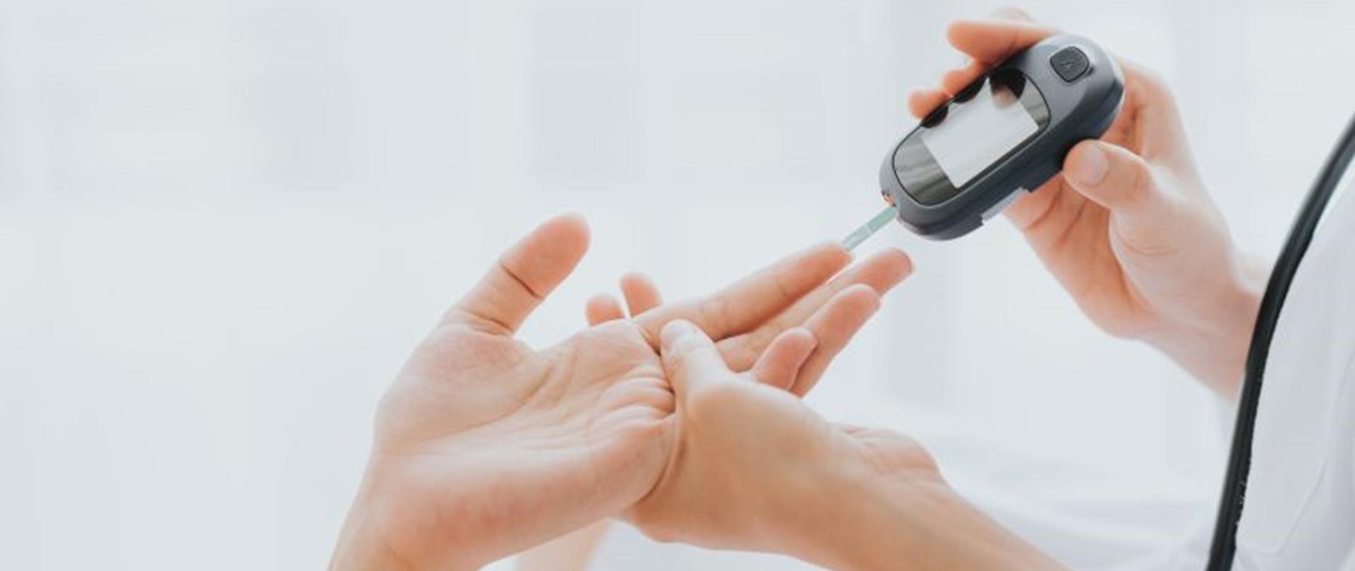 Obraz przedstawia proces mierzenia poziomu cukru glukometrem