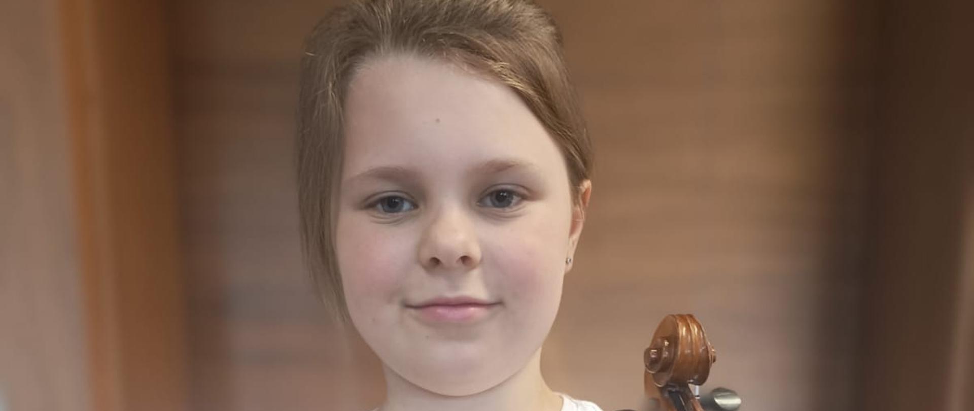 Zosia Kupny trzymająca w rękach dyplom z konkursu i skrzypce
