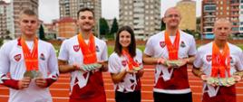 Pięciu funkcjonariuszy stoi w szeregu w miejscu rozgrywek lekkoatletycznych trzymając zdobyte medale.