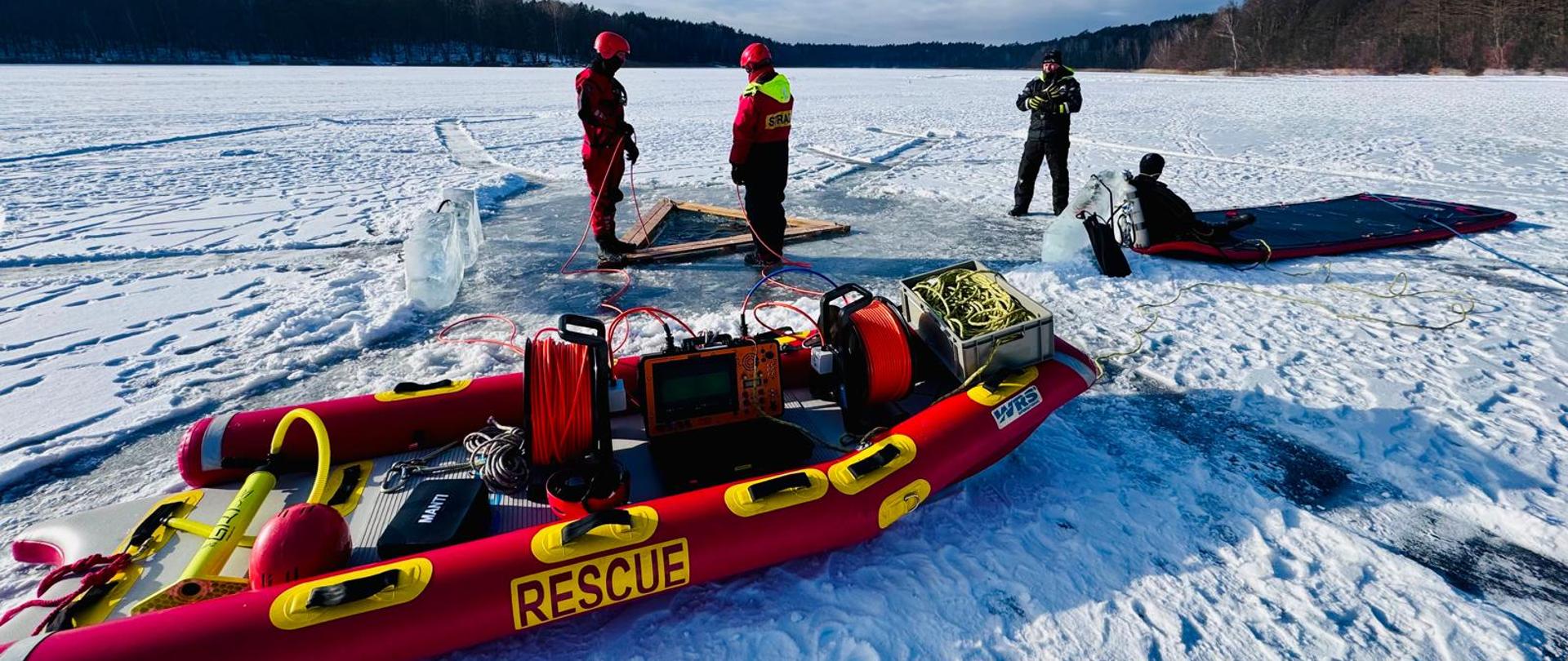Na zdjęciu widnieją strażacy w trakcie szkolenia pod lodem. 