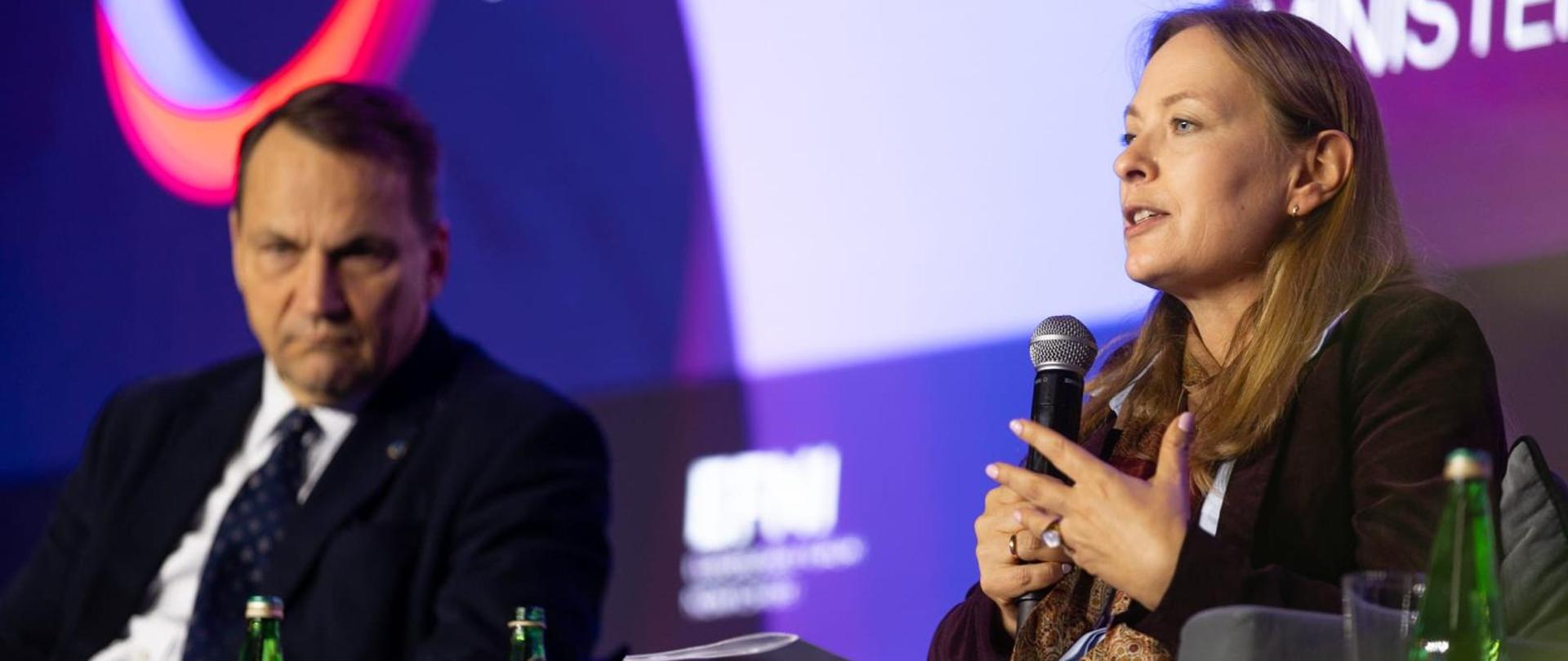 Minister Katarzyna Pełczyńska-Nałęcz siedzi i trzyma w ręce mikrofon, po jej prawej stronie siedzi minister spraw zagranicznych Radosław Sikorski