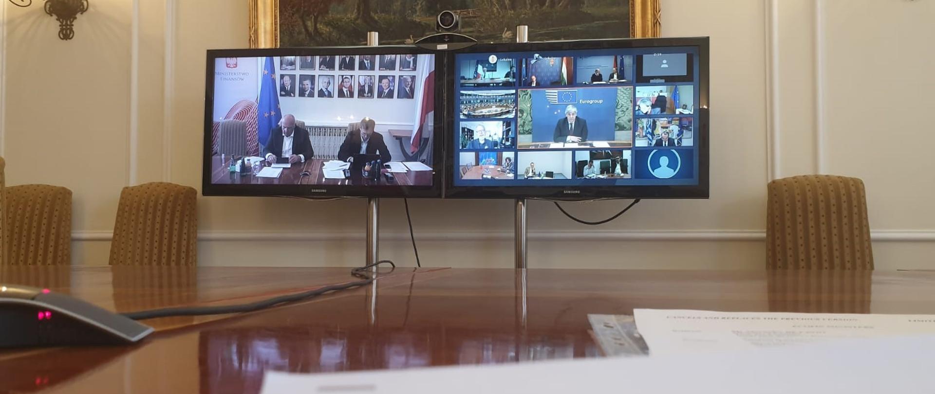 Telekonferencja eurogrupy - dwa monitory na których widać uczestników spotkania a przed monitorami dokumenty
