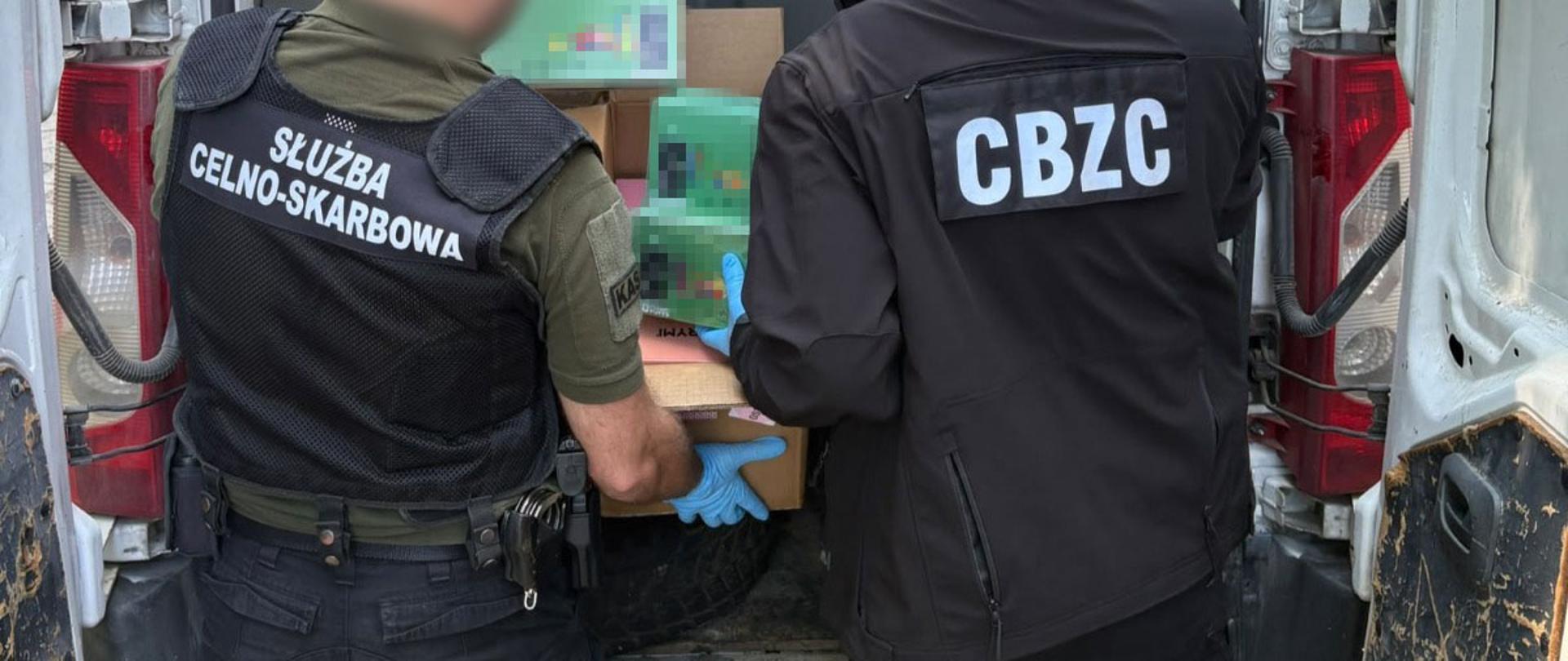 funkcjonariusze wyjmują opakowania z przestrzeni ładunkowej samochodu