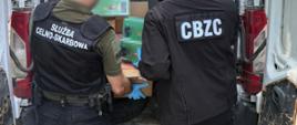 funkcjonariusze wyjmują opakowania z przestrzeni ładunkowej samochodu