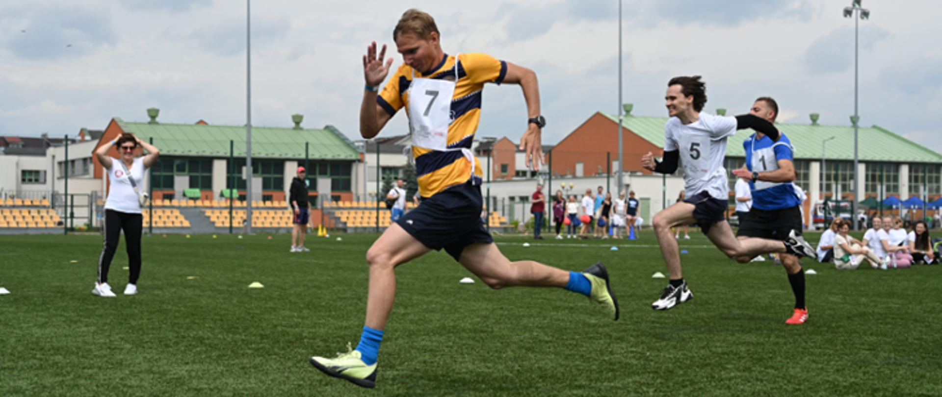 mężczyzna w czarnych spodenkach i koszulce w paski biegnie po murawie stadionu