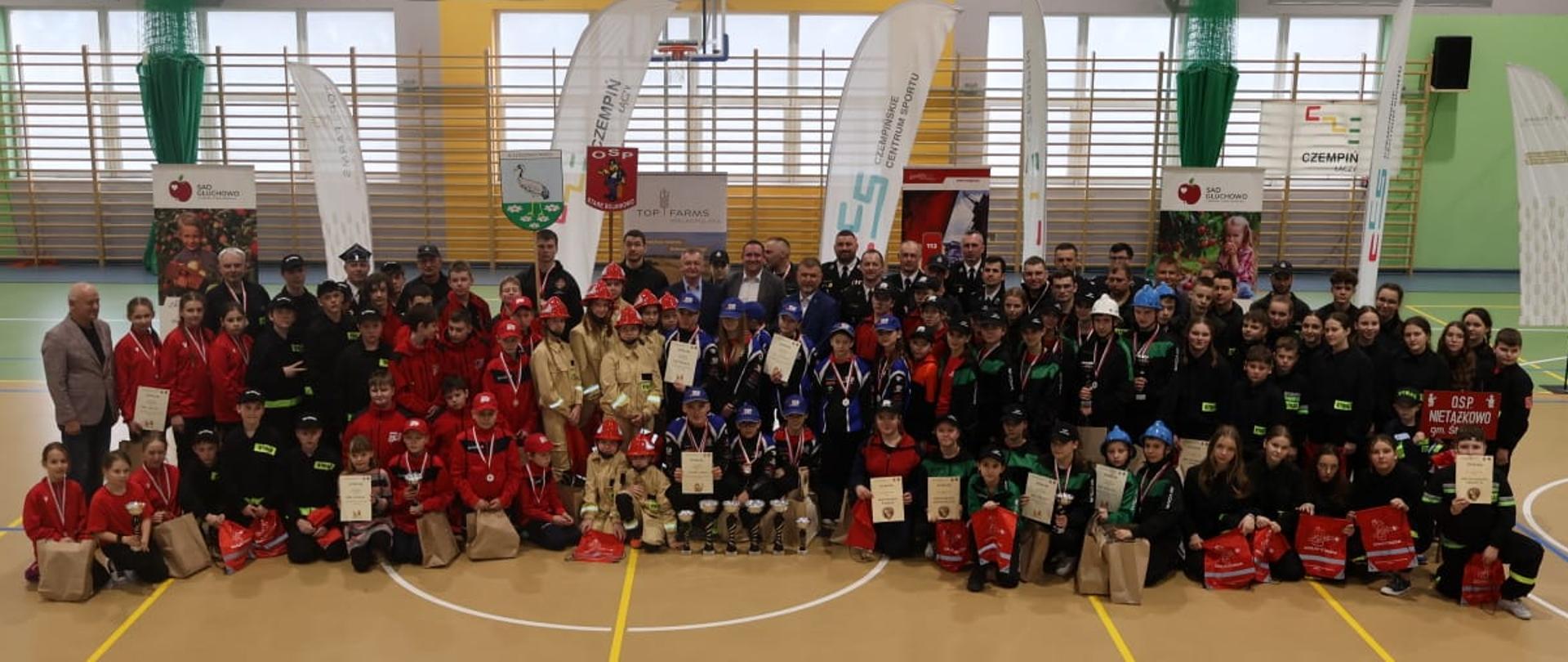 I Halowe Zawody Sportowo-Pożarnicze Powiatu Kościańskiego. Strażacy podczas dekoracji, z włodarzami i przedstawicielami instytucji. 