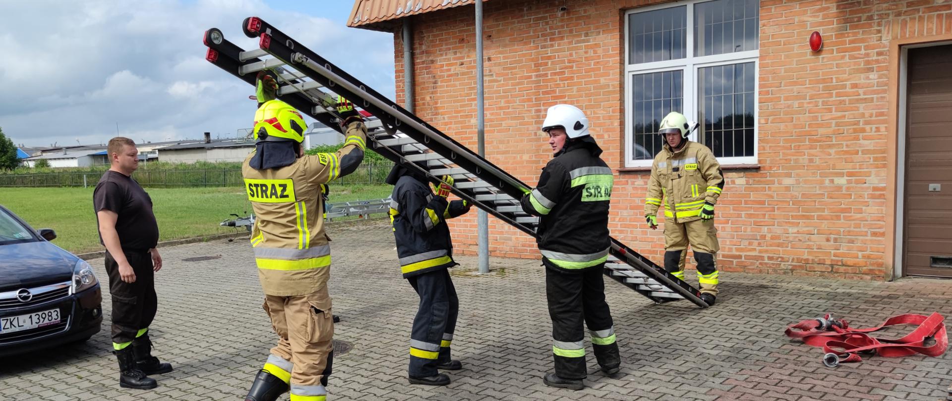 Strażacy OSP uczący się, pod nadzorem strażaka z PSP, sprawiania drabiny wysuwanej D10W.