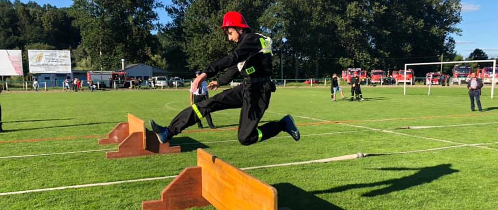 Strażak przeskakuje płotek.