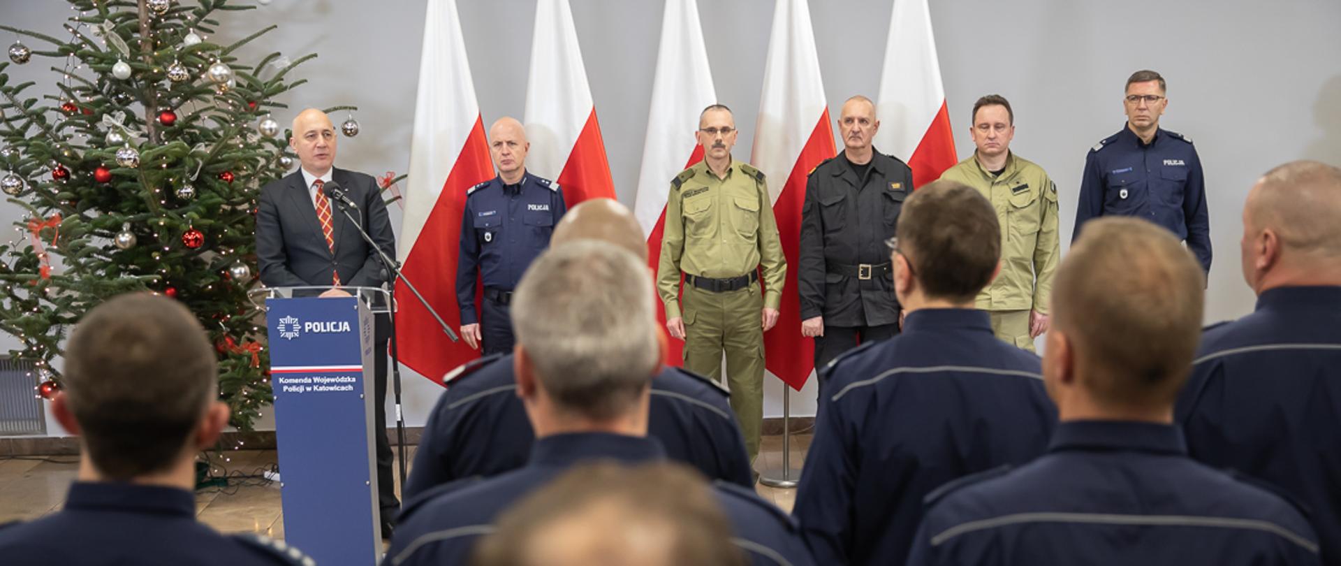 Minister Joachim Brudziński podczas przemówienia stojąc przy mównicy.