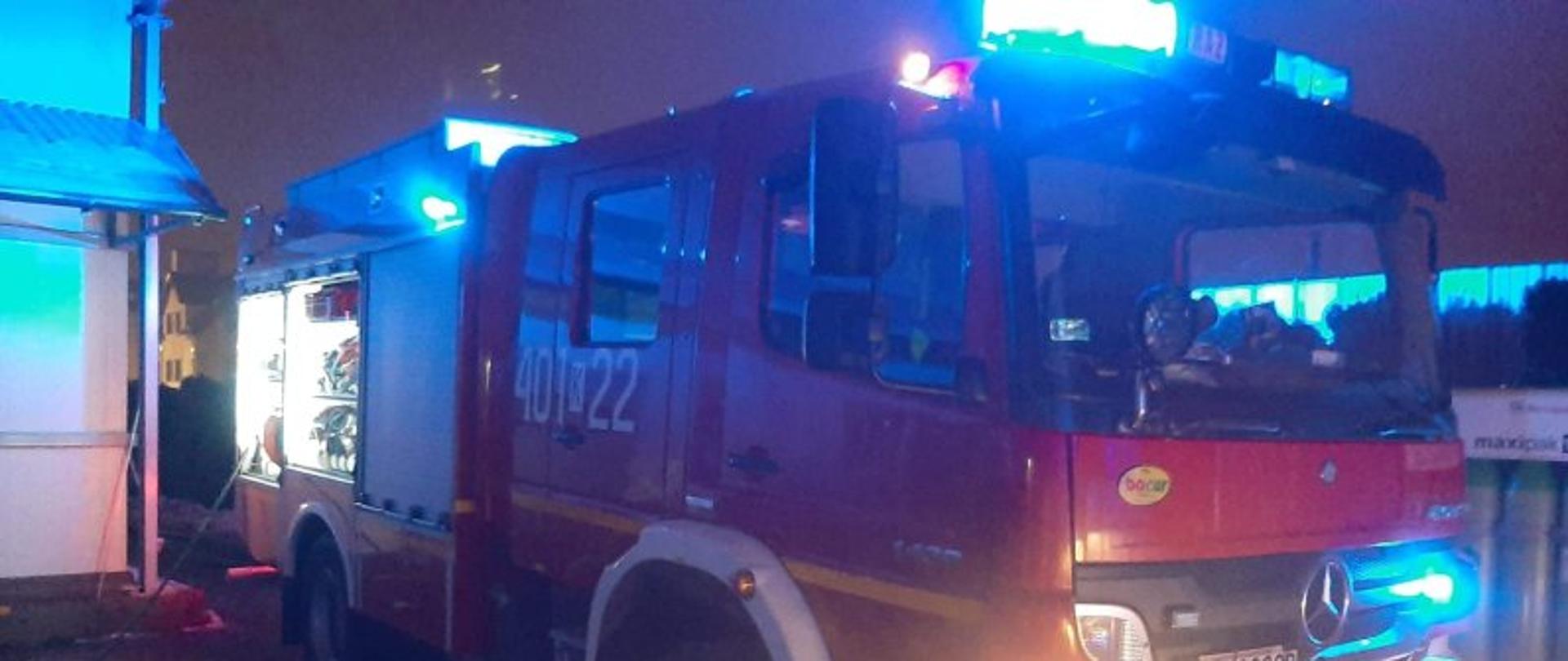 Średni samochód ratowniczo – gaśniczy GBARt 2,5/16 z JRG Bochnia o numerze 401 k 22 z którego podawany jest prąd gaśniczy. Obok widać budynek firmy Contimax SA.