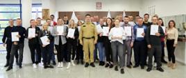 Grupowe zdjęcie uczestników szkolenia w towarzystwie Komendanta Centralnej Szkoły PSP, trzech funkcjonariuszy CS PSP i kobiety