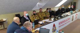 Uczestnicy spotkania siedzą przy biurku w kształcie litery U, na przodzie widnieje napis KOMENDA GŁÓWNA PSP