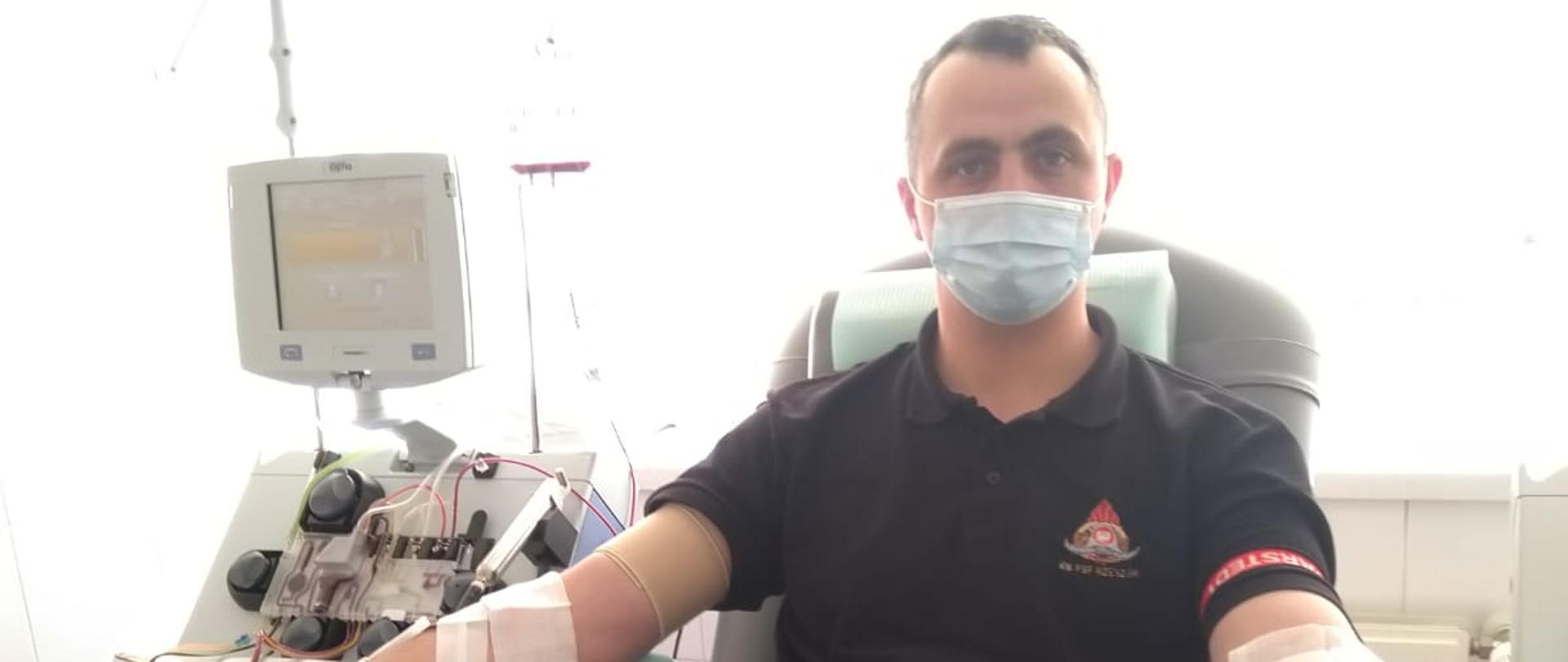 Zdjęcie przedstawia ogniomistrza Tadeusza Szopińskiego w umundurowaniu koszarowym siedzącego na fotelu podczas oddawania krwi w Regionalnym Centrum Krwiodawstwa i Krwiolecznictwa w Krakowie