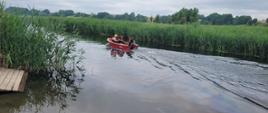 Tafla wody rzeki Brda, widoczne czcinowiska. Na tafli wody łódka straży pożarnej a na niej strażacy. 