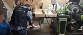 na zdjęciu funkcjonariusz KAS przy maszynie do produkcji nielegalnych papierosów