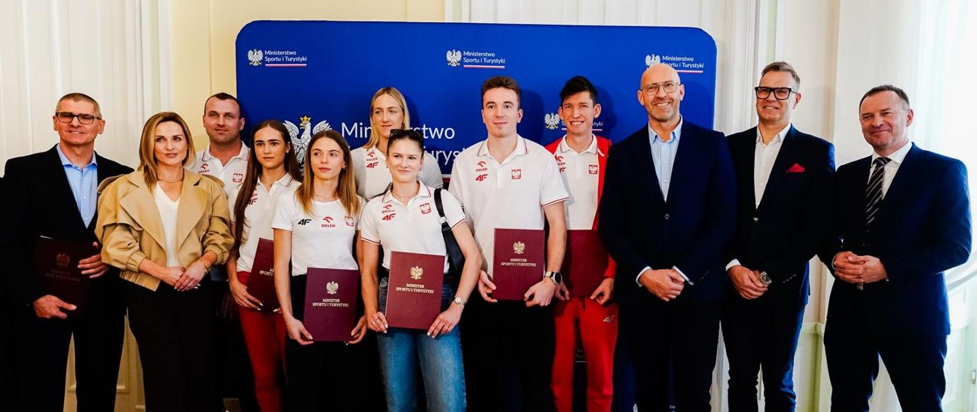 Group photo showing the medalists of the World Athletics Indoor Championships 2026, their coaches, Minister of Sport and Tourism Jakub Rutnicki, Secretary of State Piotr Borys and reprezentatives of the Polish Athletic Association. Wall with the Ministry of Sport and Tourism's logos in the background.