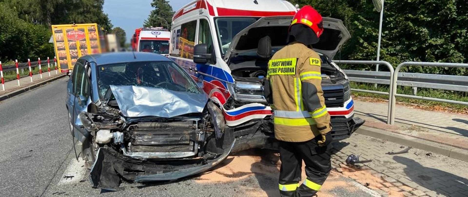 Rozbite samochody (karetka i samochód osobowy) a obok strażak.