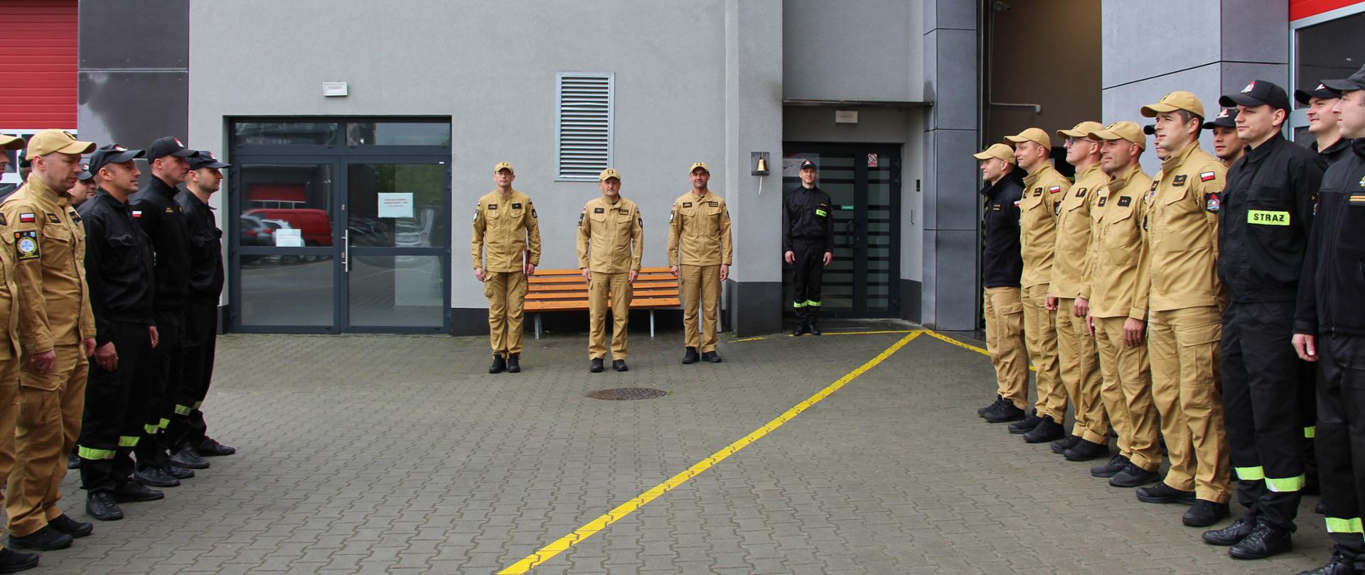 Od lewej: asp. Karol Wojteczek, Komendant Miejski PSP w Kielcach st. bryg. Mariusz Góra, zastępca dowódcy JRG Nr 1 w Kielcach st. kpt. Maciej Bartusiak stoją na zmianie służby w otoczeniu strażaków.