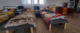 Na zdjęciu sala przygotowana do przyjęcia uchodźców. Wyposażenie sali: łóżka, wieszaki, biurko, telewizor itp.