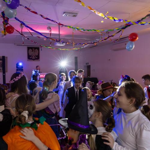 Bal karnawałowy 2024. Uczniowie i nauczyciele w przebraniach karnawałowych bawiący się na auli PSM w Głubczycach. Prowadzenie balu - Paweł Ganczarski.
