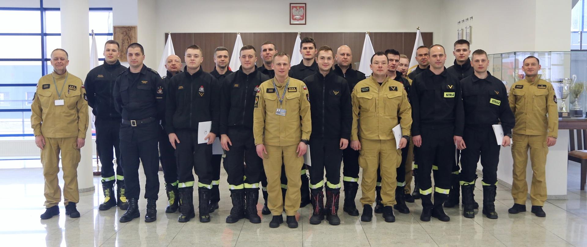 Grupowe zdjęcie uczestników szkolenia (16 funkcjonariuszy PSP) w towarzystwie Zastępcy Komendanta Centralne Szkoły PSP oraz trzech funkcjonariuszy CS PSP