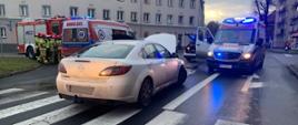 Na zdjęciu widać uszkodzony samochód osobowy, dwie karetki oraz strażaków.