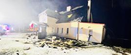 Zdjęcie przedstawia spalony budynek nocą po pożarze 